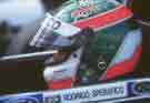 side on close up of Rodrigo Specrifico in his 
helmet sitting in his race car.